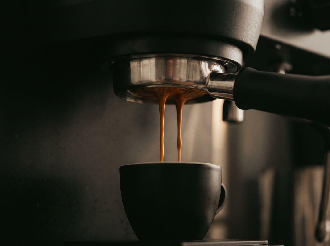 Two ropes of espresso extracting from a bottomless portafilter into a small black cup